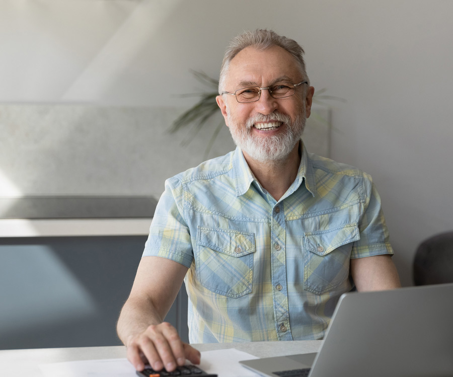 home-1398766007 Photo of happy man sitting at a computer at his desk